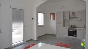 A modern kitchen with white cabinets, a built-in oven, and a hanging light fixture. - Private RED Apartment at Palma de Sols – No Shared Living Spaces (Sant'antioco)