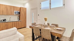 Une cuisine moderne avec des meubles en bois, un four à micro-ondes encastré et un coin repas avec une table en bois, mise pour quatre personnes.
