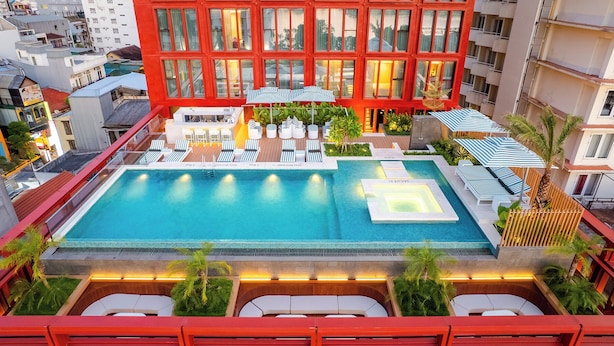 A rooftop pool area with lounge chairs, a hot tub, and a view of the cityscape. - Le Carré Hue (Hue)