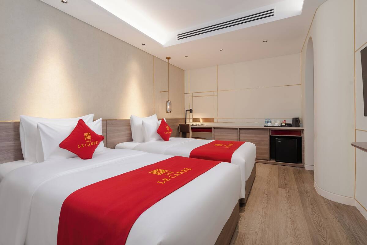A hotel room with two beds, a desk, and a kitchenette.