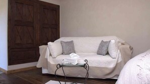 A room with a white sofa, a wooden wardrobe, and a small table with a white cloth. - Gîte de Jassenove (Jassenove-du-Larzac)