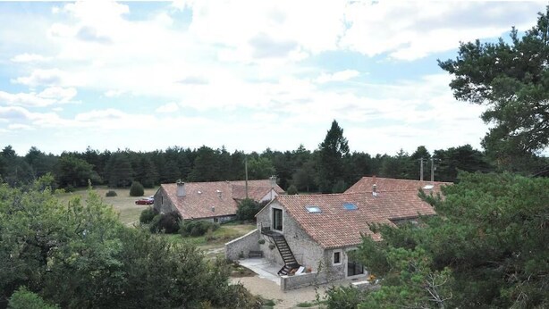 A cluster of stone houses with tiled roofs, surrounded by dense trees and a clear sky. - Gîte de Jassenove (Jassenove-du-Larzac)