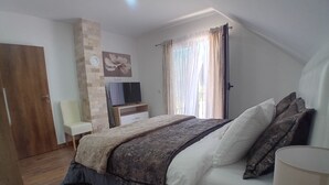 Ein Schlafzimmer mit einem Bett, einem Sessel, einem Fernseher und einem Fenster mit Vorhängen.