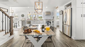 Cozinha ampla com ilha de mármore, eletrodomésticos de aço inoxidável e um lustre moderno.