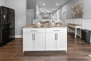 A kitchen with a marble countertop, white cabinets, and a black refrigerator.