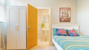 A bedroom with a bed, a wardrobe, a bathroom, and a cityscape artwork on the wall. - Chic Loft Apartment in Kelham Island, Sheffield (South Yorkshire)