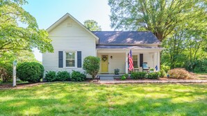 A single-story house with a front porch, a small front yard, and an American flag. - Bluebird Cottage in heart of Hickory, NC (Hickory)