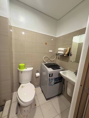 Une petite salle de bain comprenant des toilettes, un lave-linge et un lavabo.
