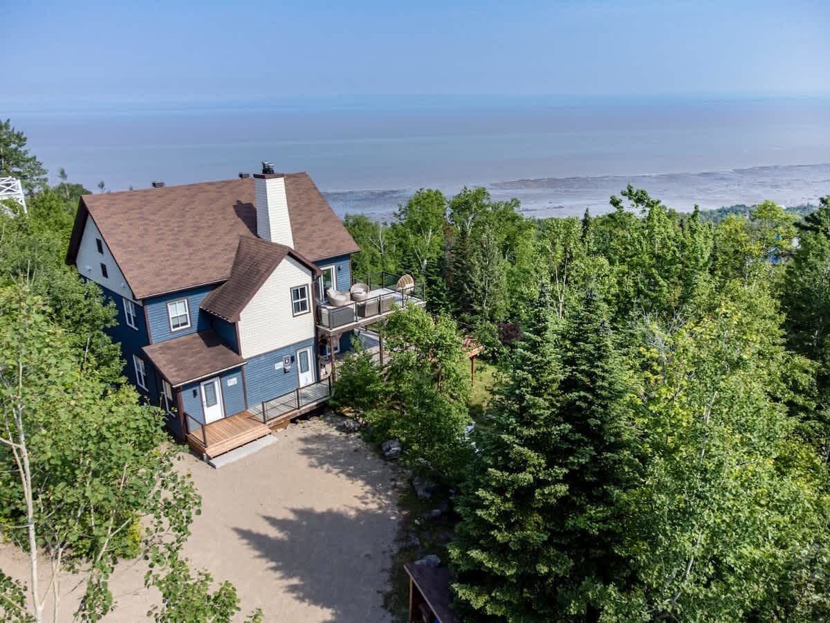 A two-story house with a balcony overlooking a beach.