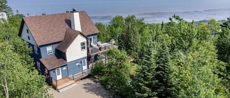 A two-story house with a balcony overlooking a beach.