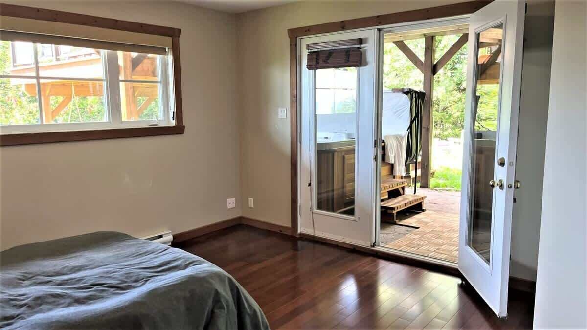 A bedroom with a bed, a window, and a sliding glass door leading to an outdoor patio.