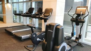 Une salle de sport équipée de vélos d’appartement, de tapis de course et d’un appareil elliptique.