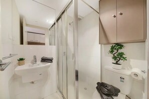 Een moderne badkamer met een douchecabine van glas, een wastafel met een klein plantje en een toilet met een potplant.