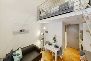 Een ruimtelijk ingerichte leefruimte met slaaploft, een eethoek en een kleine kitchenette.