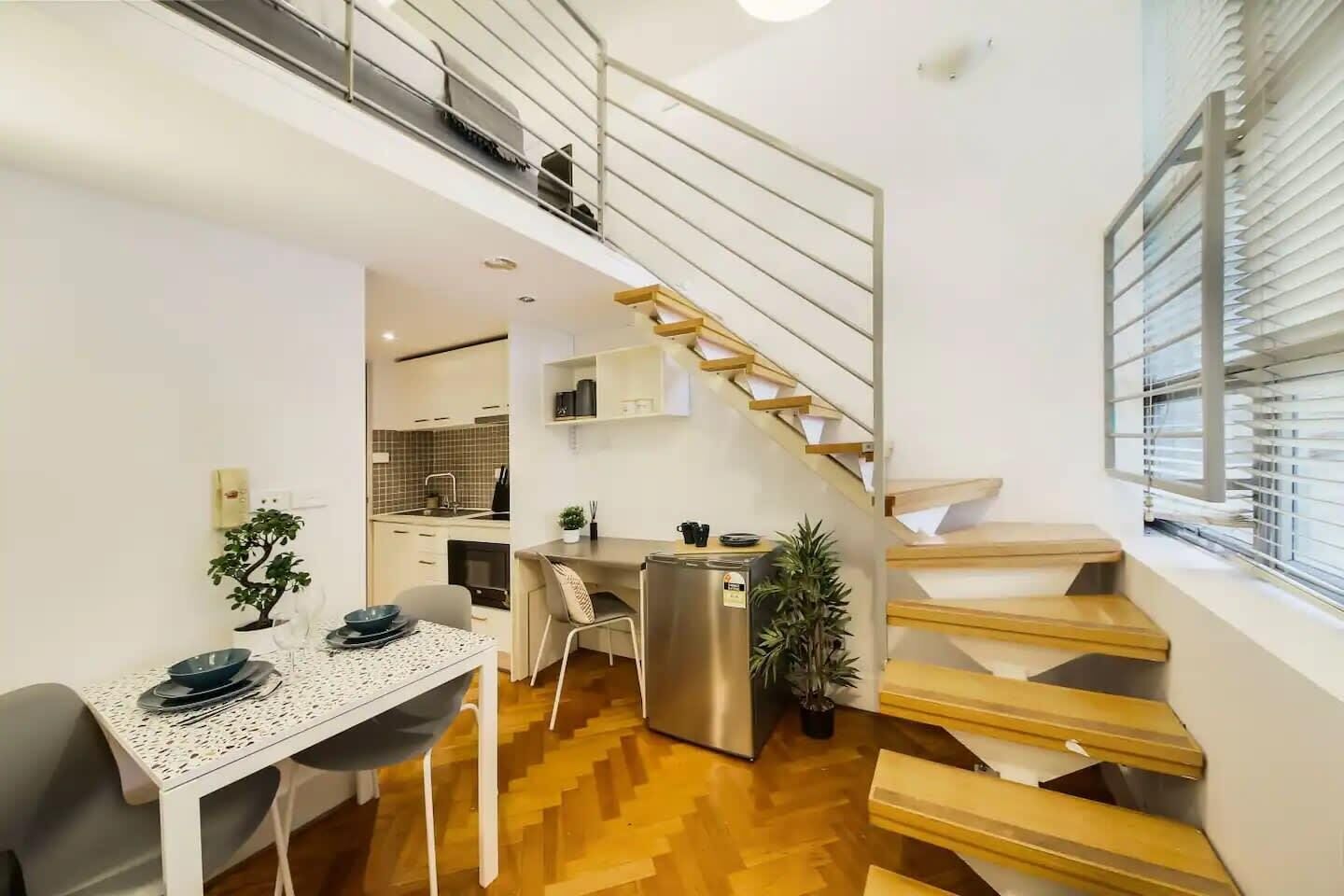 Een modern appartement met een keuken, eethoek en een houten trap.