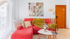 Un salon avec un canapé rouge, une table basse blanche et une porte en bois.