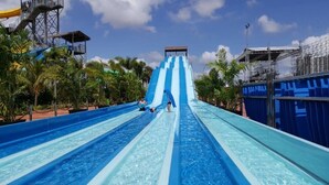 A water slide with multiple lanes, surrounded by palm trees and a clear sky. - 3BR D'Pristine Suite Near LEGOLAND, Stunning Views (Nusajaya)