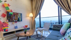 A modern hotel room with a large window, a television, a sofa, a small table, and a colorful play area. - 3BR D'Pristine Suite Near LEGOLAND, Stunning Views (Nusajaya)