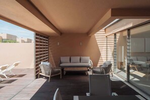A sunlit outdoor patio with a sofa, two chairs, and a table.