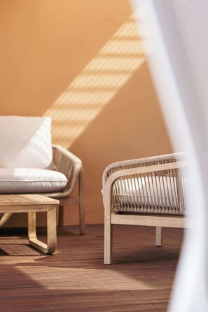 A wicker chair and a sofa in a room with wooden flooring and a plain wall. - 2BR Villa w/ Private Pool | Salgados | DA’Home (Guia)