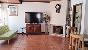 Un soggiorno con televisione a schermo piatto, divano, camino e zona pranzo.