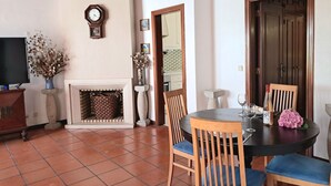 Un'area pranzo con un tavolo rotondo, sedie, un camino, una sveglia e un televisore.