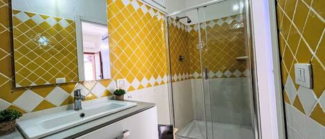 A bathroom with a large mirror, a sink, and a shower area.