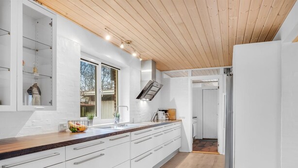 Una cocina moderna con armarios blancos, encimera de madera y horno integrado.