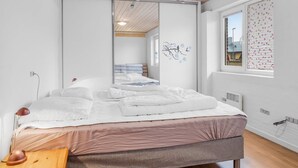 Un dormitorio con una cama, un espejo, una ventana con persianas y techo de madera.