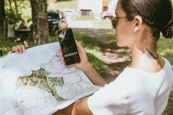 Una persona sosteniendo un teléfono inteligente y un mapa, probablemente para orientarse.