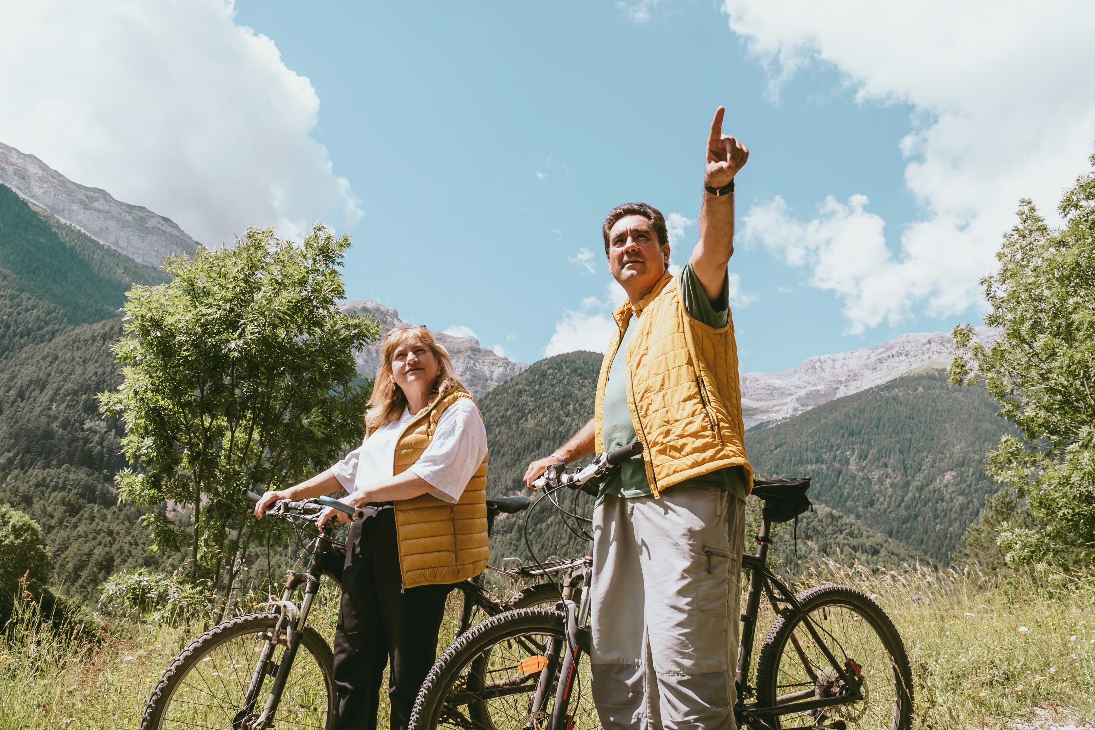 Dos personas con bicicletas en un paisaje montañoso.