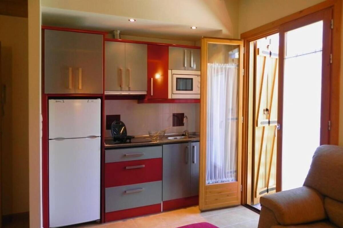 A compact kitchen with a refrigerator, microwave, and a dining area with a table and chairs.