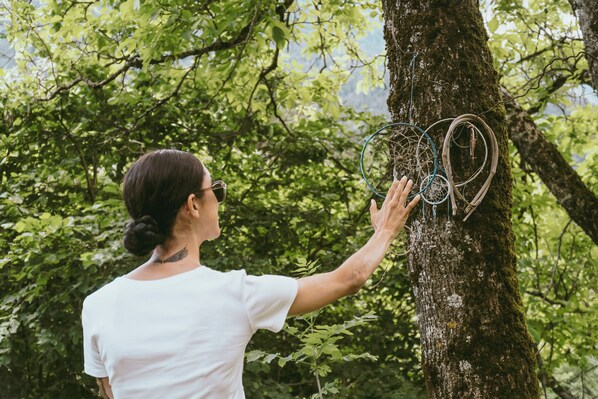 A person interacting with a tree that has dreamcatchers hanging from it. - Caserón Baruca (Bielsa)