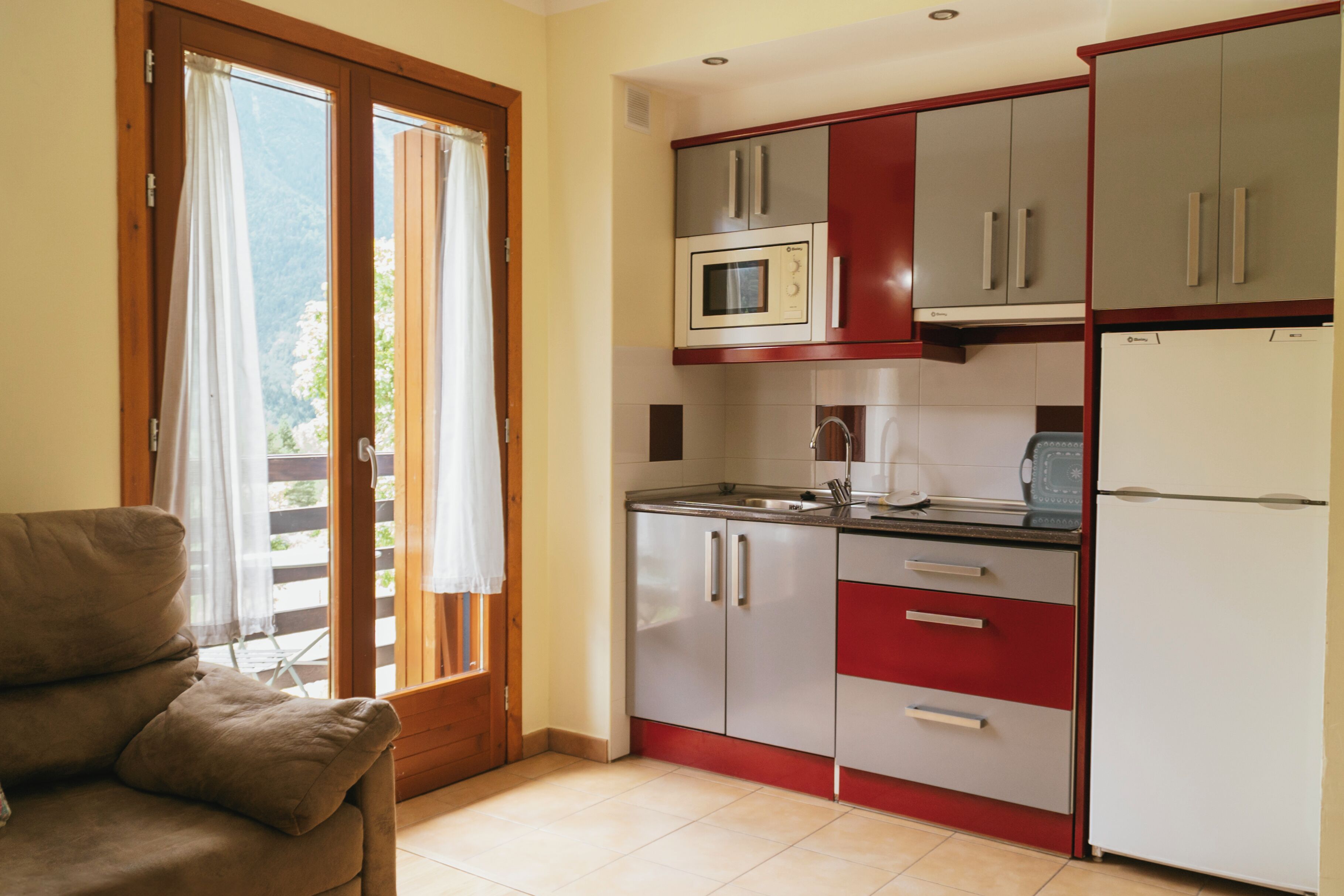 A kitchen with a microwave, refrigerator, and cabinets.