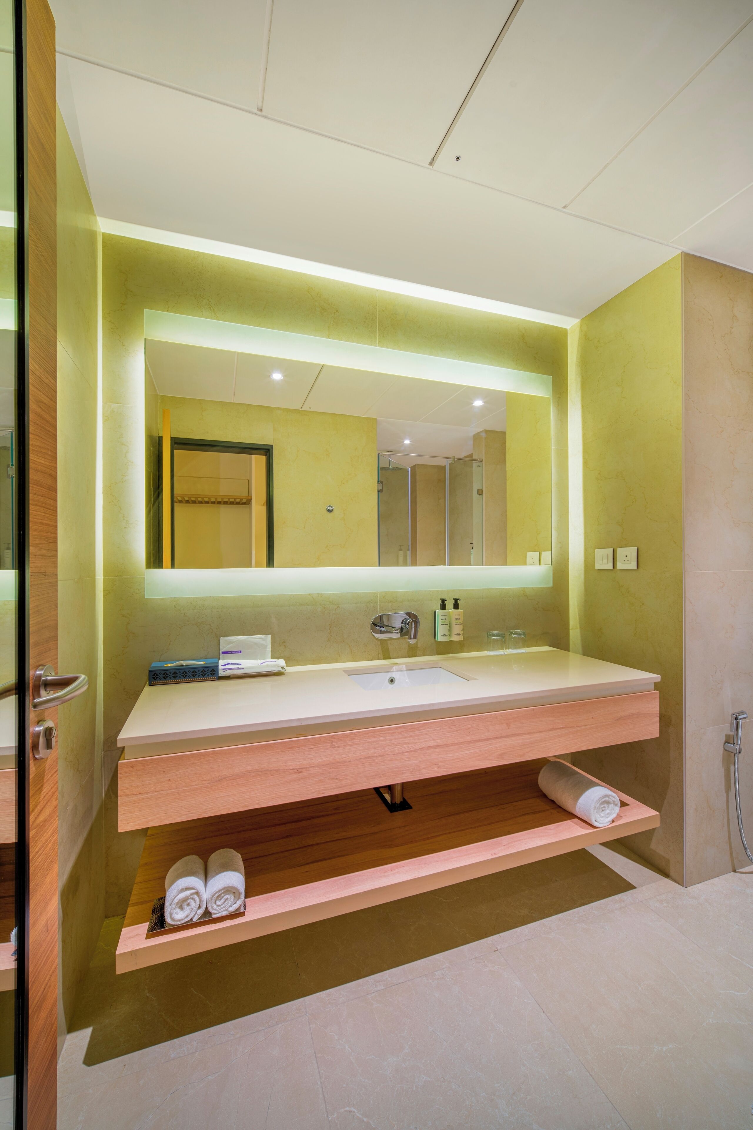 A modern bathroom with a large mirror, a sink, and a towel rack.