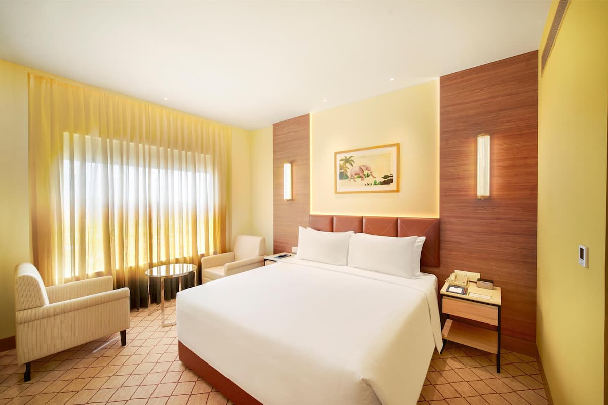 Une chambre d’hôtel avec un grand lit, une table de chevet avec une lampe, une chaise et une petite table.