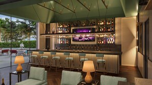 Een bar met een televisiescherm, barstoelen en een zithoek met tafels en stoelen.