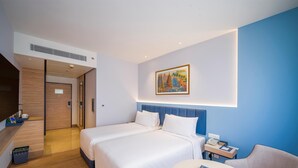 Hotelkamer met een groot bed, een bureau met stoel, een schilderij aan de muur en een blauwe accentmuur.