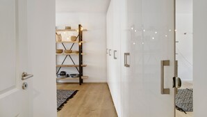 A modern interior with a white door, a wooden shelf with baskets, and a patterned rug. - Apartment 'Lieblingsplatz' with Mountain View, Private Terrace and Wi-Fi (Bad Tölz)