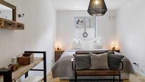 A bedroom with a bed, bedside tables, a hanging light fixture, a window with blinds, and a wooden bench. - Apartment 'Lieblingsplatz' with Mountain View, Private Terrace and Wi-Fi (Bad Tölz)