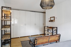 A bedroom with a wooden bed, white wardrobe, and a hanging light fixture.