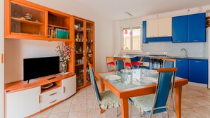 Un espacio habitable compacto con comedor, cocina y mueble de entretenimiento.