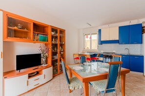 A compact living space with a dining area, kitchen, and entertainment unit.
