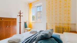 Una habitación de hotel con cama, armario de madera, ventana con cortinas y radiador.