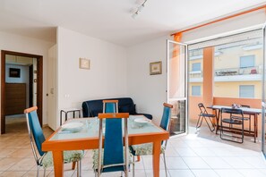 Un comedor con mesa y sillas, un sofá, y un balcón con vistas.