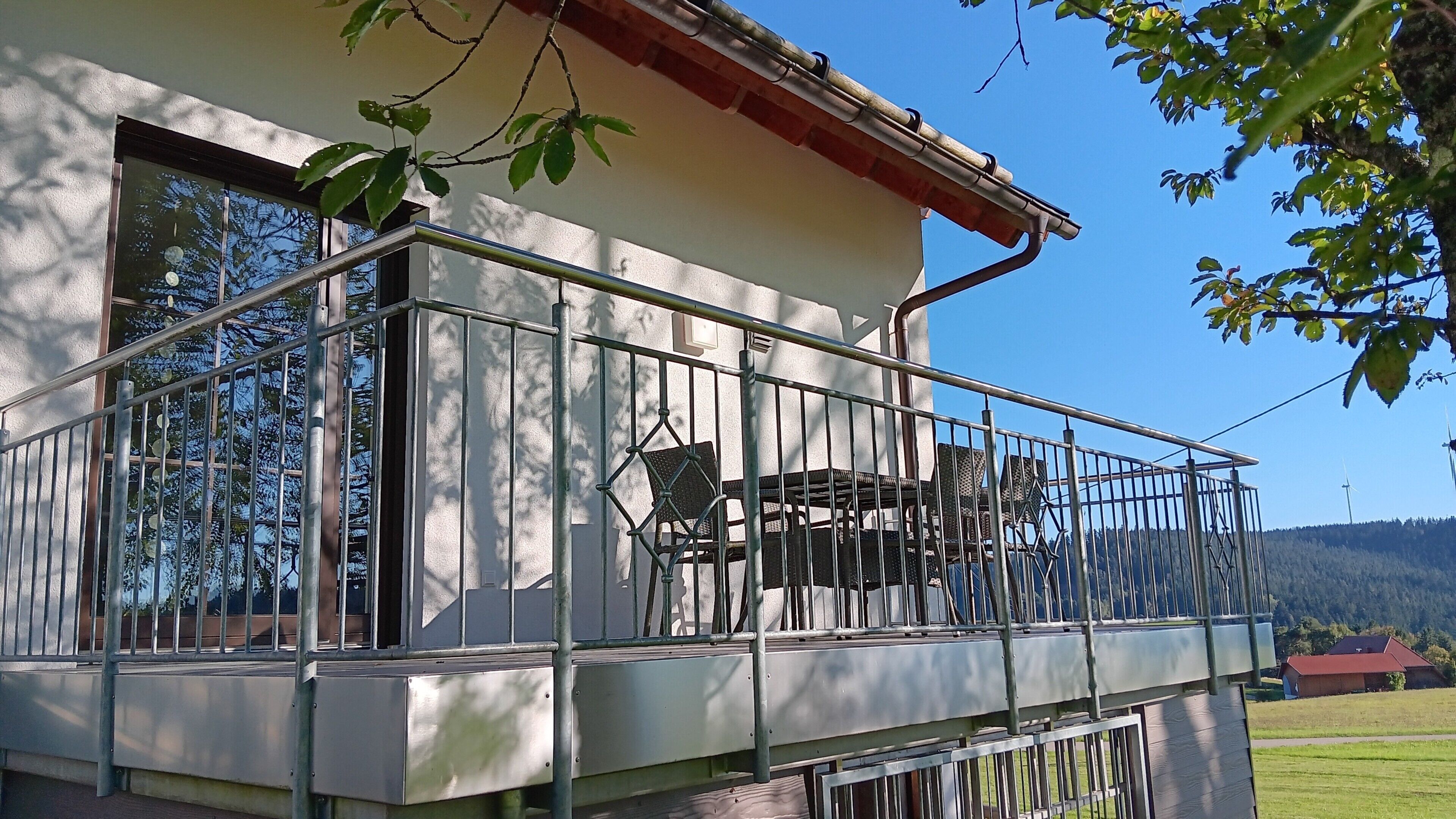 A balcony with metal railings, a window, and a view of the surrounding landscape.
