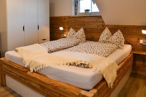 Een tweepersoonsbed met bloemenbeddengoed, een houten hoofdbord, nachtkastjes met lampen en een garderobe.
