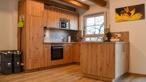Eine Küche mit Holzausstattung, einer Mikrowelle, einem Backofen und einem Fenster mit Blick.