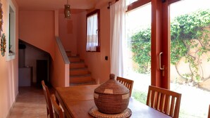 A dining area with a wooden table, chairs, a decorative vase, and a staircase leading to another room. - Casa Marzia by Wonderful Italy (Olbia)