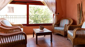 A balcony with wicker furniture, a table, and a view of greenery. - Casa Marzia by Wonderful Italy (Olbia)